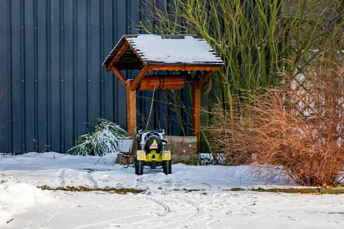 Robotgräsklippare och laddstation utomhus i vinterlandskap med snö